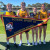 Four students hold a plaque and a large flag that reads 'School Sport SA Champion School' after winning the A2 Grade of the statewide athletics championships