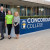 Concordia's Director of Information and Learning Technologies and Concordia Campus Principal standing with Kate from Good360 Australia alongside the Concordia College sign on Winchester Street, Highgate